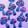 Sticker holographique d'un champignon bleu et rouge avec des pois blancs, il est accompagné de petites étoiles qui renforcent son côté magique.