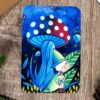 la petite sorcière en robe verte se tient joyeusement près d’un grand champignon rouge à pois blancs, qui semble tout droit sorti d’un conte de fées.