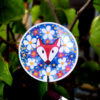 Sticker holographique d'un renard entouré de fleurs, le sticker scintille grâce au papier holographique, ce qui renforce son côté magique.