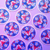 Sticker holographique d'un renard entouré de fleurs, le sticker scintille grâce au papier holographique, ce qui renforce son côté magique.